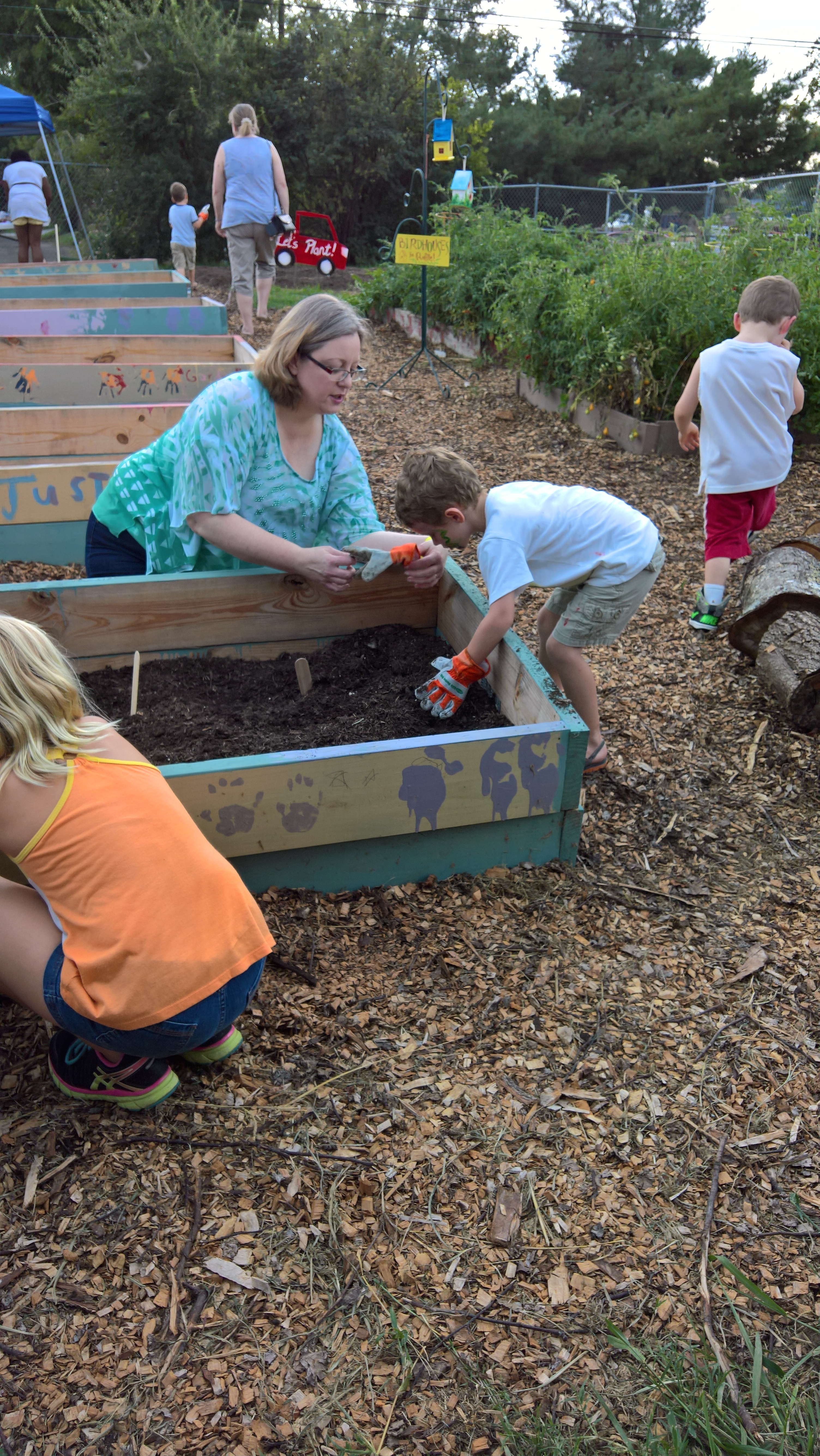 Inskip Community School Garden Ribbon Cutting 2016. Jennifer Owen plants carrots with a students.